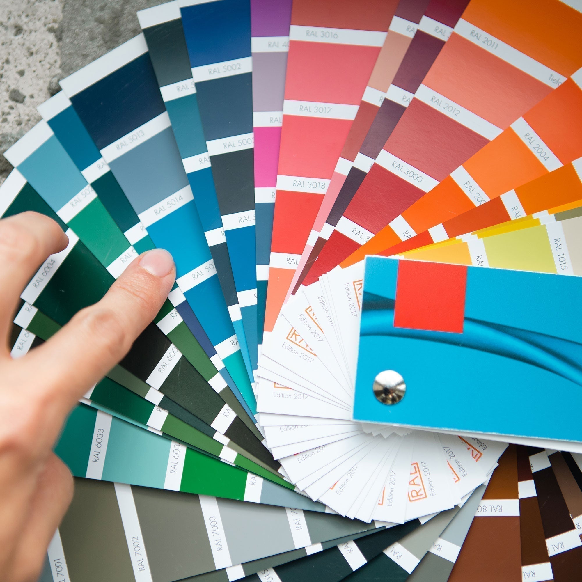 Ein Fächer mit den verschiedenen RAL-Farben und einer Hand