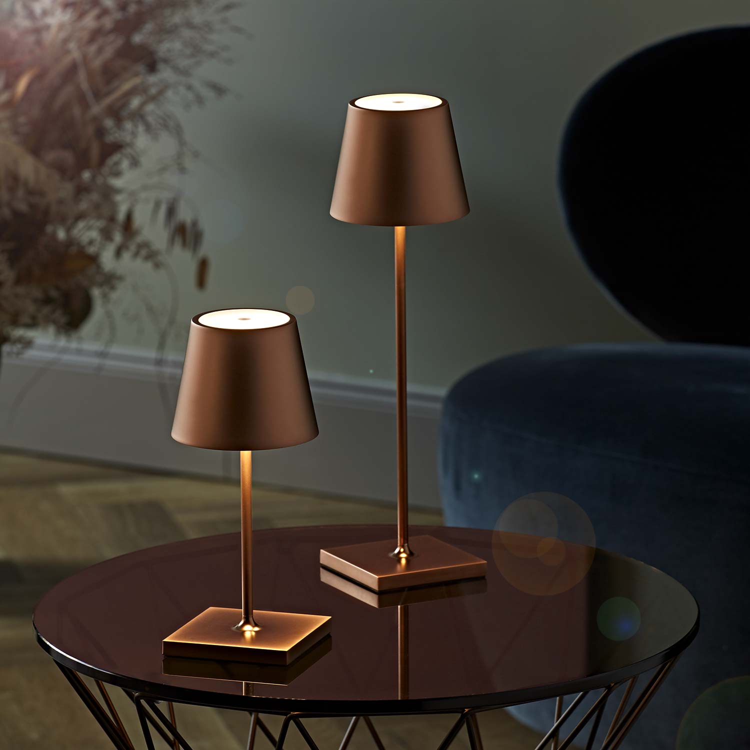 Die Sigor Nuindie Akku-Tischleuchte in bronze metallic und 2 Größen auf einem Beistelltisch