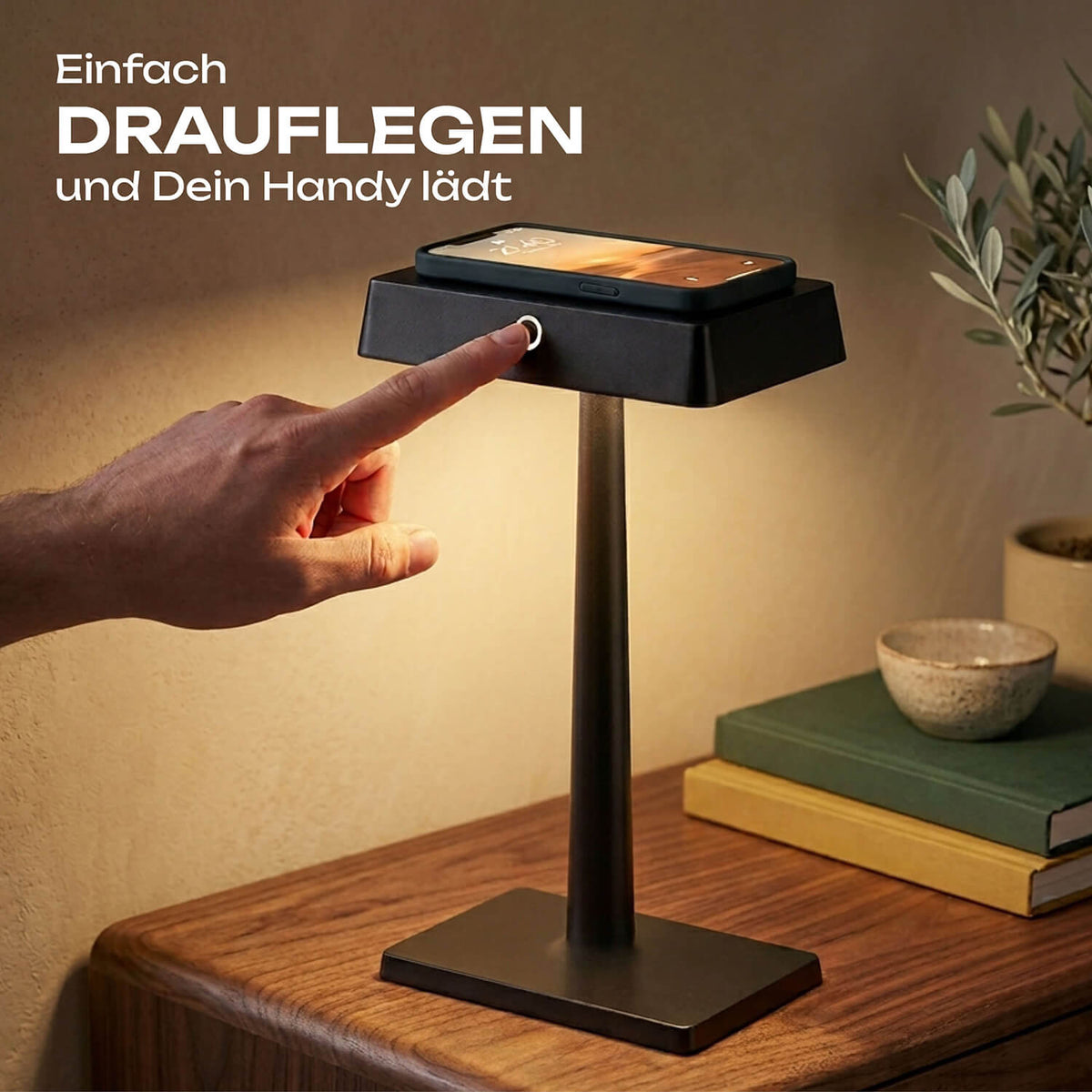 Schwarze Sigor Nucharge Akku-Tischleuchte mit Qi-Ladefunktion, auf ihr lädt ein Smartphone, ein Finger tippt auf den Touch-Schalter #Farbe_Nachtschwarz