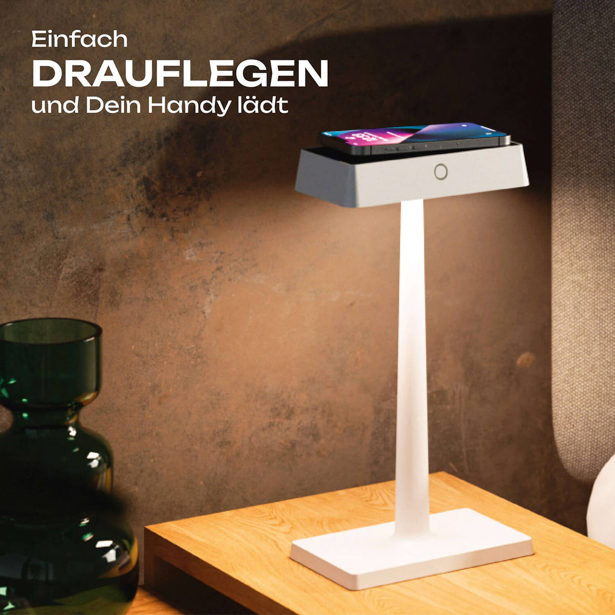 Weiße Sigor Nucharge Akku-Tischleuchte mit Qi-Ladefunktion, auf ihr lädt ein Smartphone #Farbe_Schneeweiss